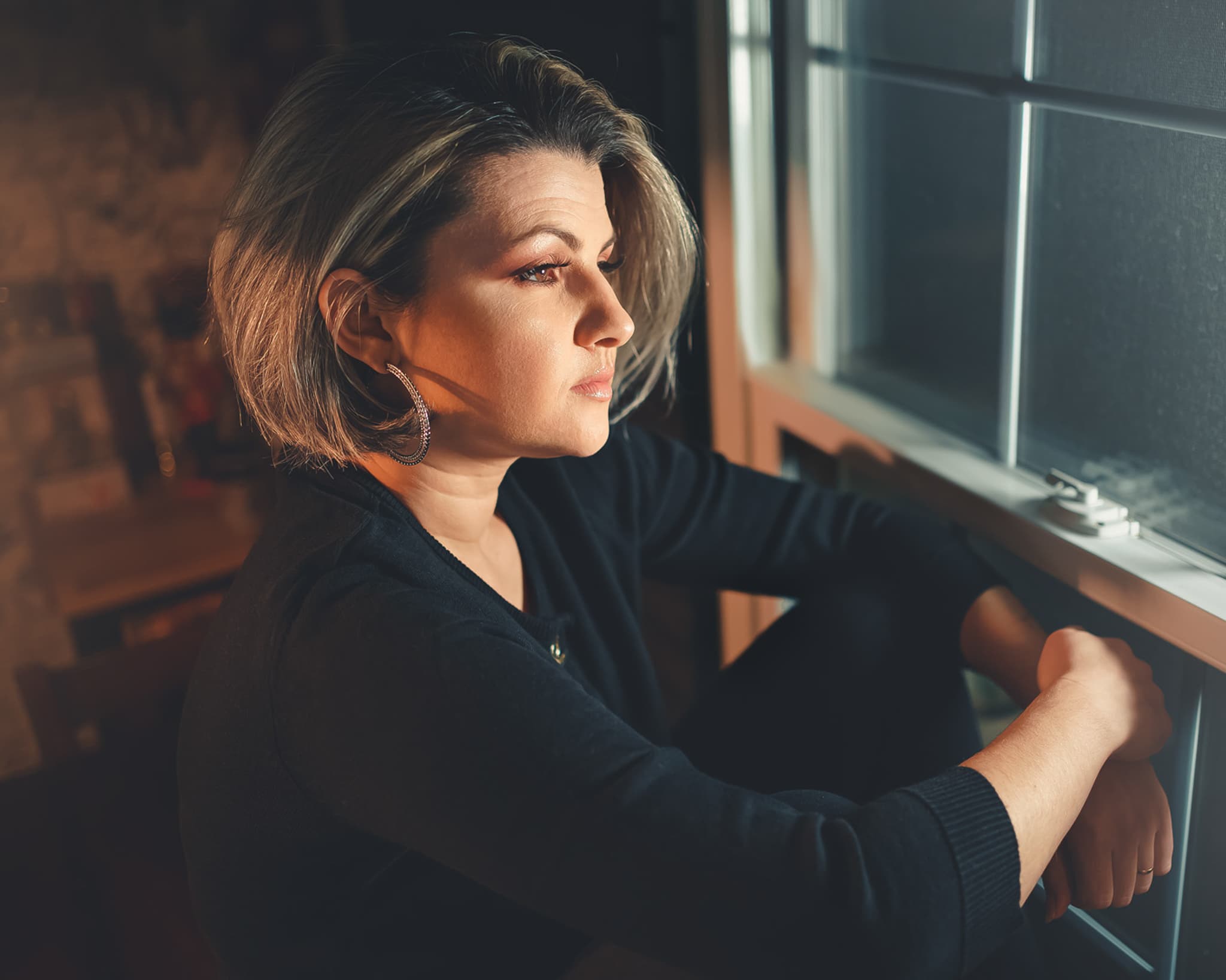 Woman gazing out window in amber light
